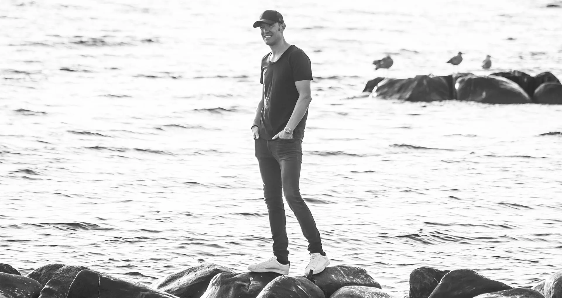 Ulrik Lynge står på sten ved vandkanten og ser ud over havet.
